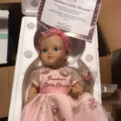 Value of an Ashton Drake Porcelain Doll - doll wearing a pink dress with embroidered flowers