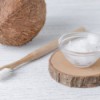 Coconut oil in a small bowl next to a coconut and a toothbrush.