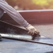 Someone laying down roofing tar paper.