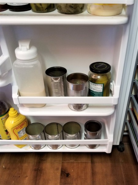 Cans in the refrigerator to stabilize and contain condiments.