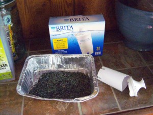 Repurpose Spent Water Filter Cartridges - charcoal from a water filter in an aluminum baking pan