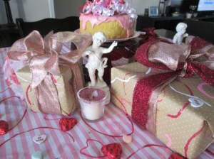 Recycled Paper Rolls as Heart Stamps - packages wrapped in the stamped paper sitting on a table covered with pink and white striped fabric stamped with red hearts