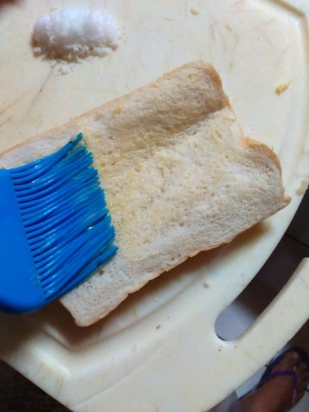 brushing bread with garlic butter