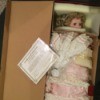Determining the Value of a Porcelain Doll Collection - doll wearing a pink dress wrapped in plastic in a cardboard box