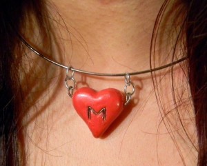 A necklace with a big red heart and a "M".