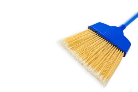 A blue broom with yellow bristles on a white background.