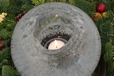 Round ice candle surrounded by greenery.