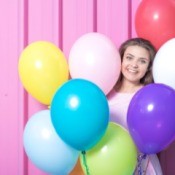 Young girl surrounded by colorful balloons.