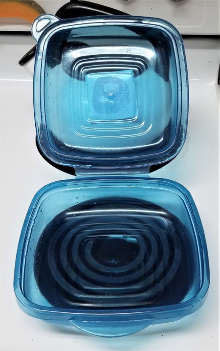 A plastic food storage container with an attached lid.