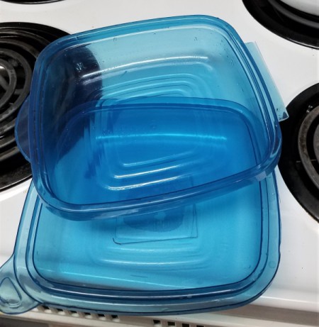 A plastic food storage container with a detached lid.