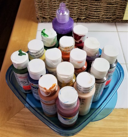 A collection of paints in a plastic container.