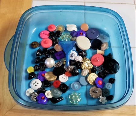 A collection of buttons in a plastic container.