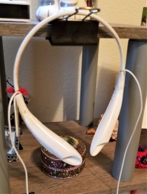 A binder clip holding a pair of bluetooth headphones.