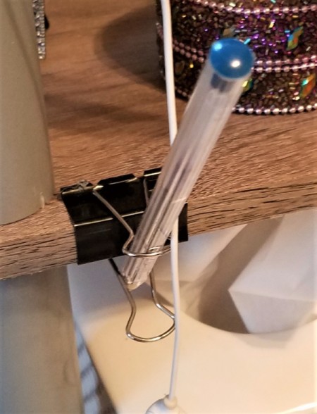 A binder clip holding a pen.