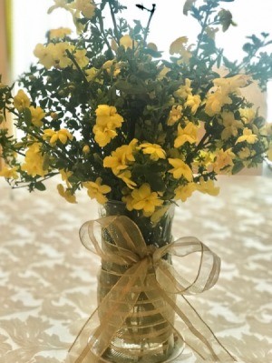 Yellow flowers in a vase decorated with ribbon.