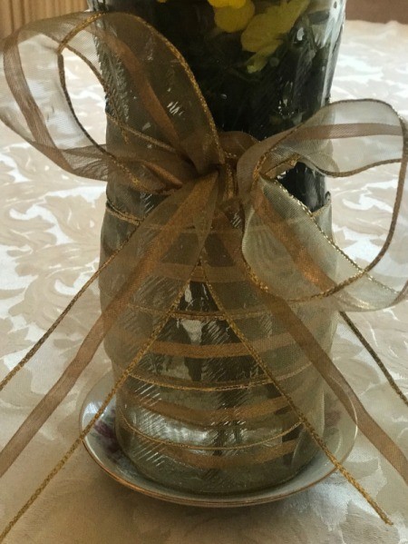 Yellow flowers in a vase decorated with ribbon.