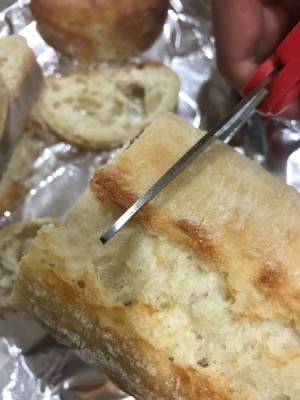 A loaf of bread being cut with a pair of scissors.