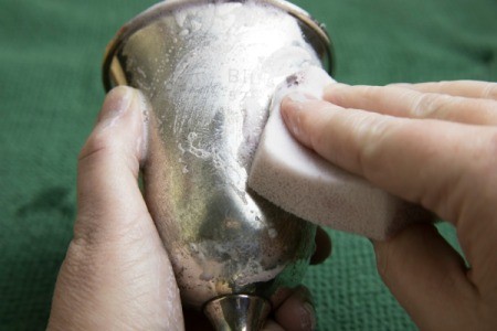 A silver goblet being polished.