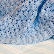 A blue blanket crocheted with a shell pattern.