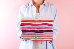 A woman holding a stack of folded laundry