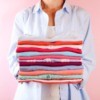 A woman holding a stack of folded laundry
