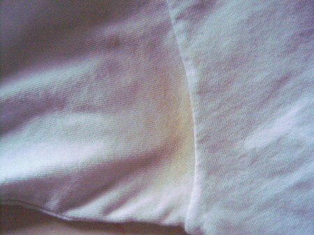 A yellow underarm perspiration stain on a white T-shirt.