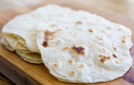 Homemade Tortillas piled on a cuttingboard