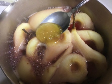 adding honey to pear halves in pan