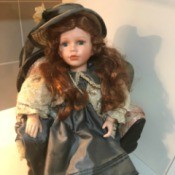 Identifying a Porcelain Doll - doll wearing a gray dress and matching hat