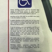 A gas station sign with information for handicapped customers.