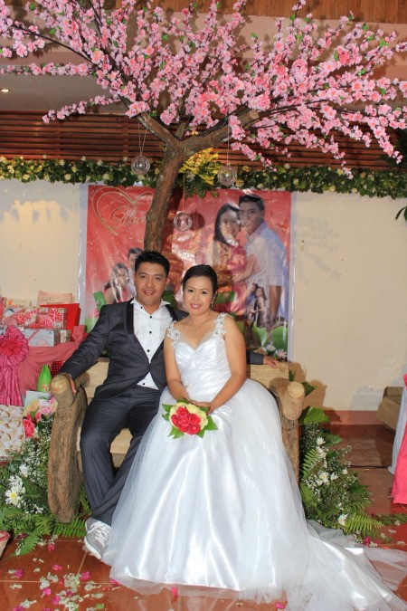 The married couple under a tree with pink flowers.