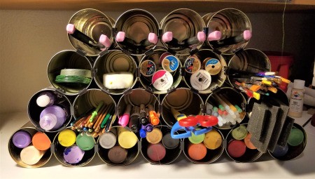 Tin Can Craft Supply Organizer - filled with supplies, can lids placed under bottom row to tilt it back a bit, see final photo