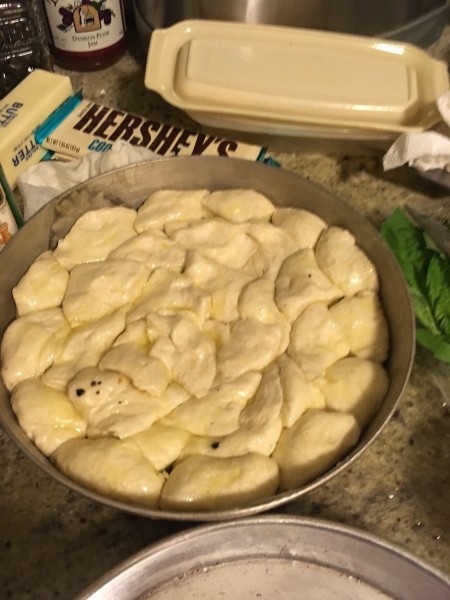 A round cake pan filled with pieces of refrigerator biscuits.