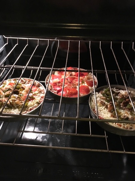 Three pizzas with different toppings in the oven.