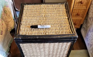 A scratched wicker hamper with a black Sharpie on top.