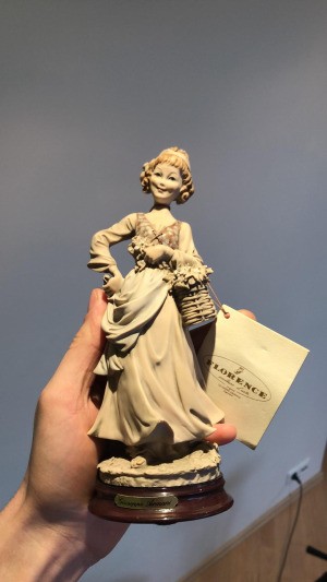 Value of a Giuseppe Armani Figurine - hand holding a tan figurine