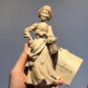 Value of a Giuseppe Armani Figurine - hand holding a tan figurine