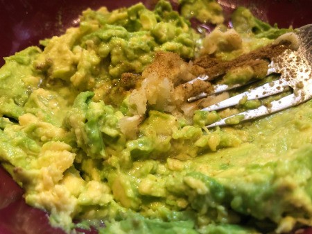 adding spices to Avocado & mixing with fork