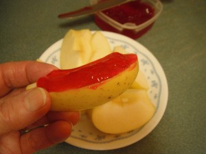 An apple slice with strawberry glaze topping it.