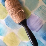 A recycled lint roller being reused as a twine dispenser.