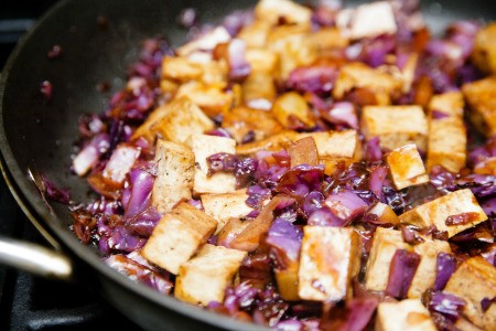 A wok with tofu and vegetables being stir fried.