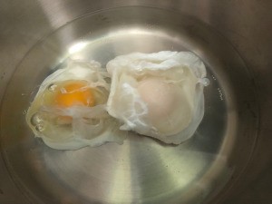 Two eggs poaching in water.