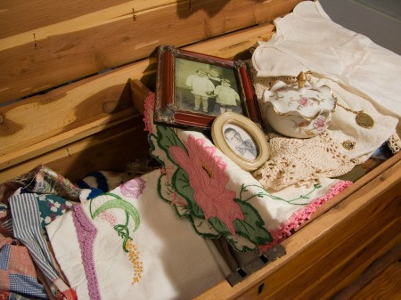 A hope chest with old fashioned linens and photos.