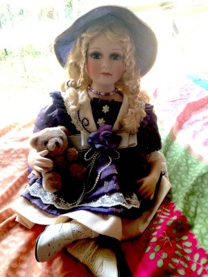 Value of Porcelain Dolls - doll wearing a hat and holding a teddy bear