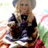 Value of Porcelain Dolls - doll wearing a hat and holding a teddy bear