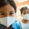 Two girls with masks on to prevent respiratory infections.