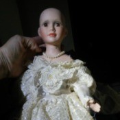 Identifying a Porcelain Doll - hairless doll wearing a pretty lacy dress and pearls
