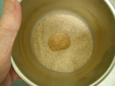 rolling ball of dough in cinnamon sugar coating
