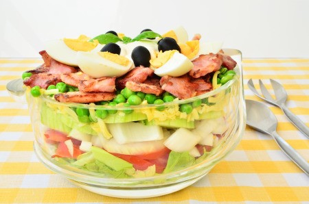 A green layered salad in a clear bowl.