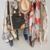 A hanging coat rack with hat, scarves and purses stored on it.